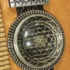 Sacred geometry pendant featuring etched Sri Yantra design under glass dome on black leather strap